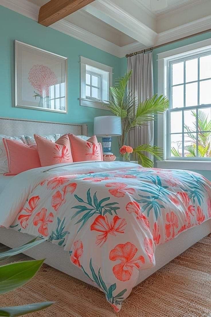 Bedroom with teal walls, large windows, and a bed featuring coral and white floral bedding, illuminated by natural light.