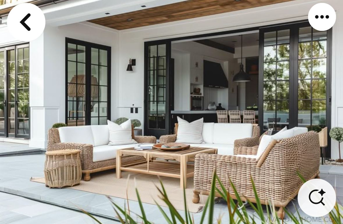 Covered patio with wicker outdoor sofa and chairs, light cushions, and a coffee table.