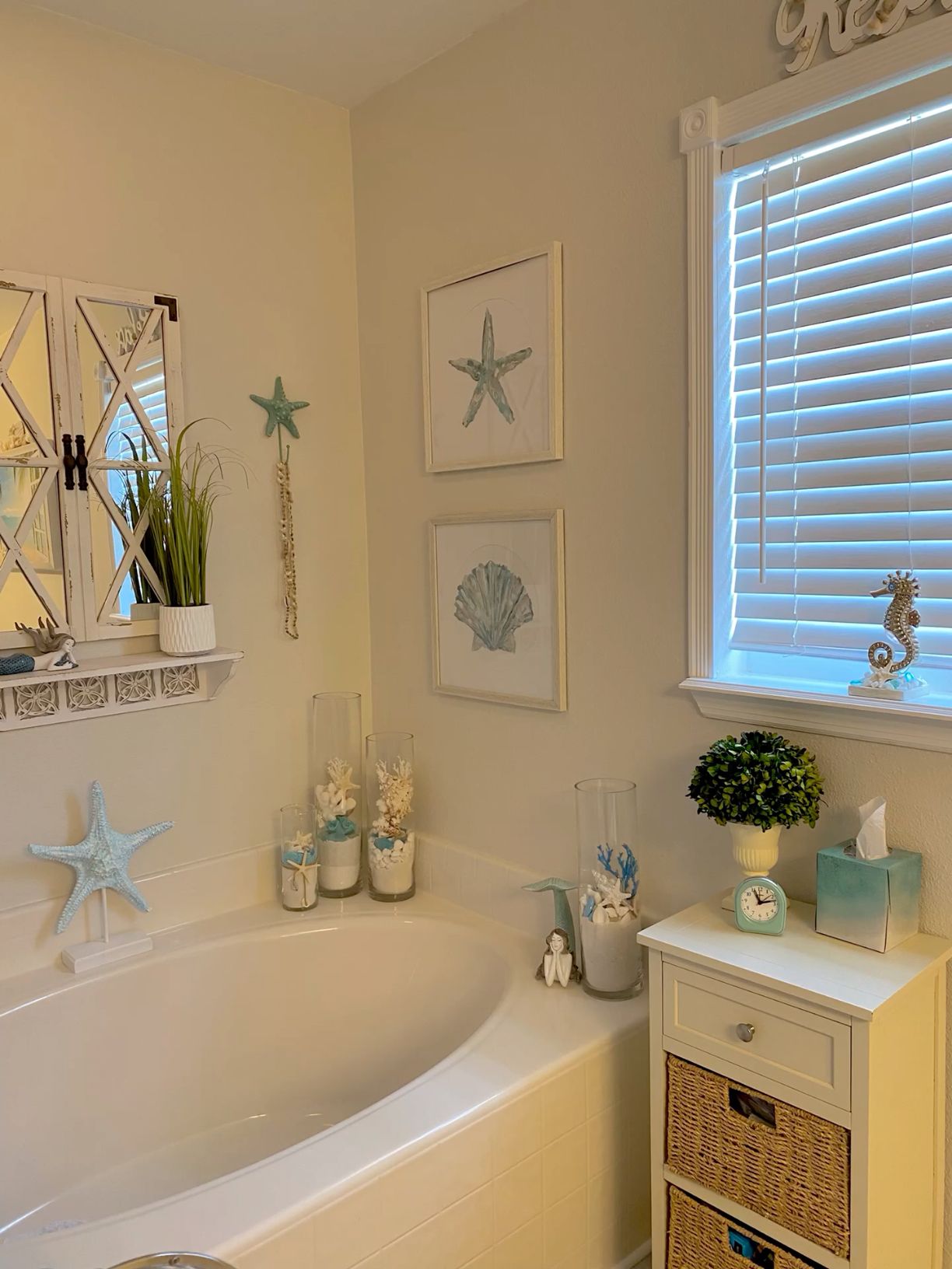 Bathroom featuring a bathtub, wall art with starfish and seashell designs, and various decorative items arranged around the…