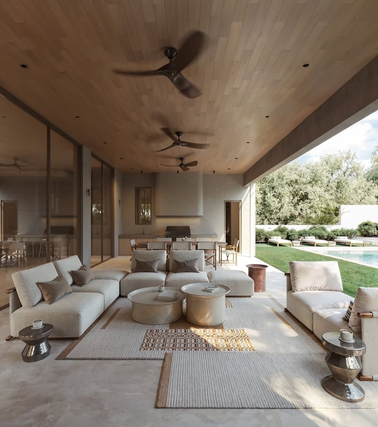 An expansive outdoor covered patio features modular white sofas, round coffee tables, and ceiling fans.