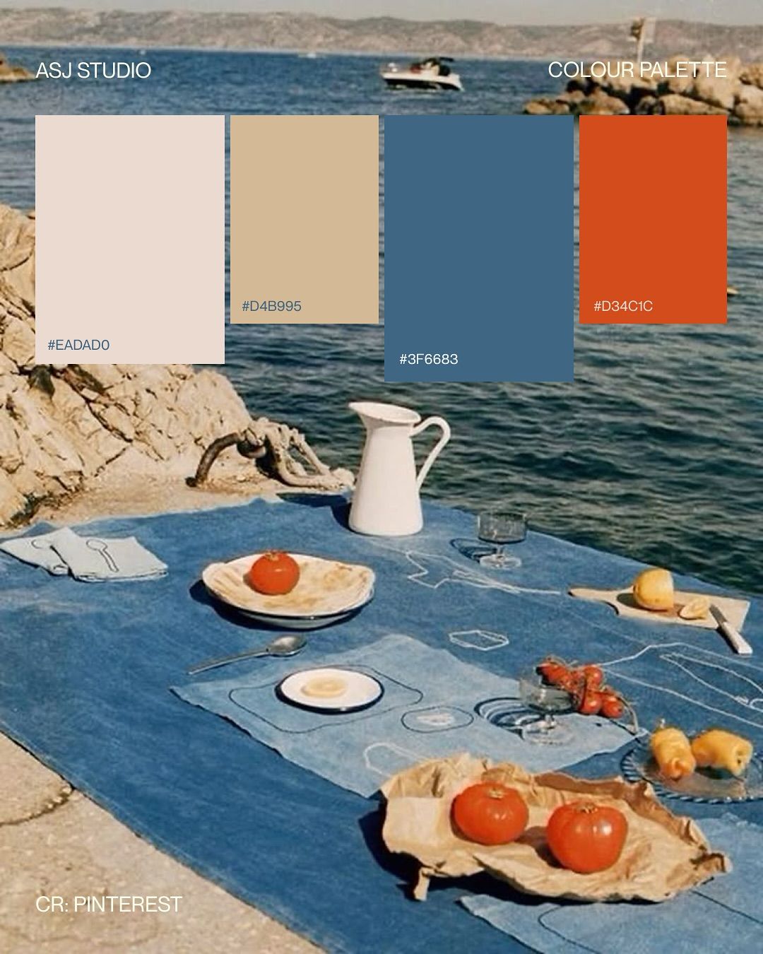 A picnic blanket spread on concrete beside the sea, with a pitcher, plates of food, and lemons, under a color palette.