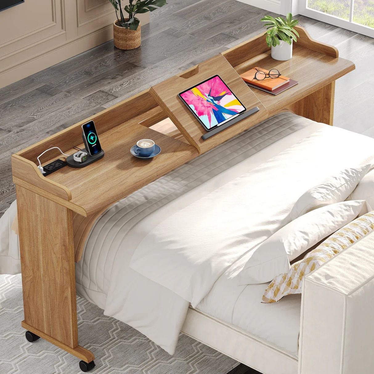 Wooden over-bed desk with a tablet, coffee cup, and charging station, positioned over a white bed.