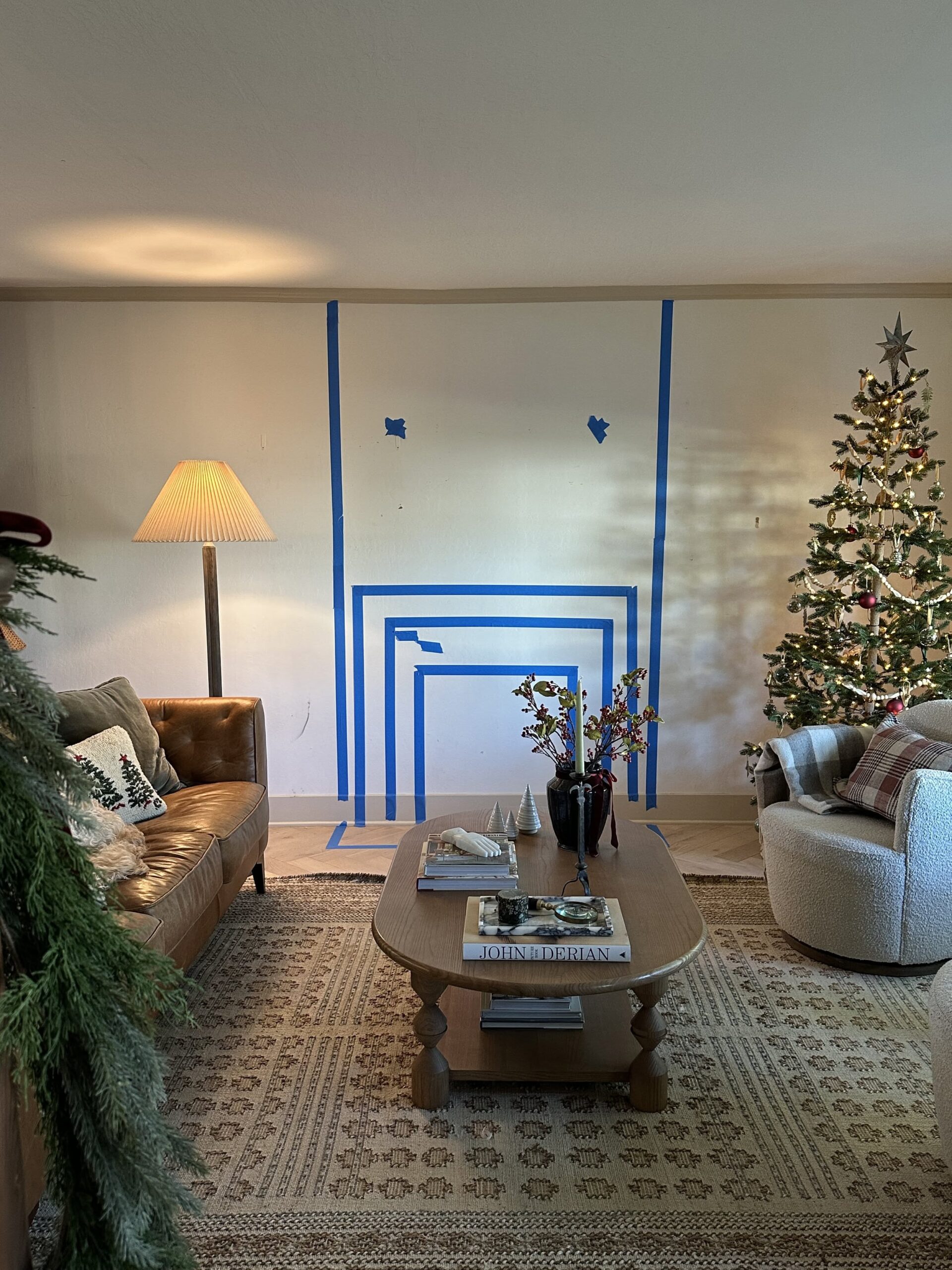 Painter's tape outlines a fireplace and mantel design on a white wall in a living room.
