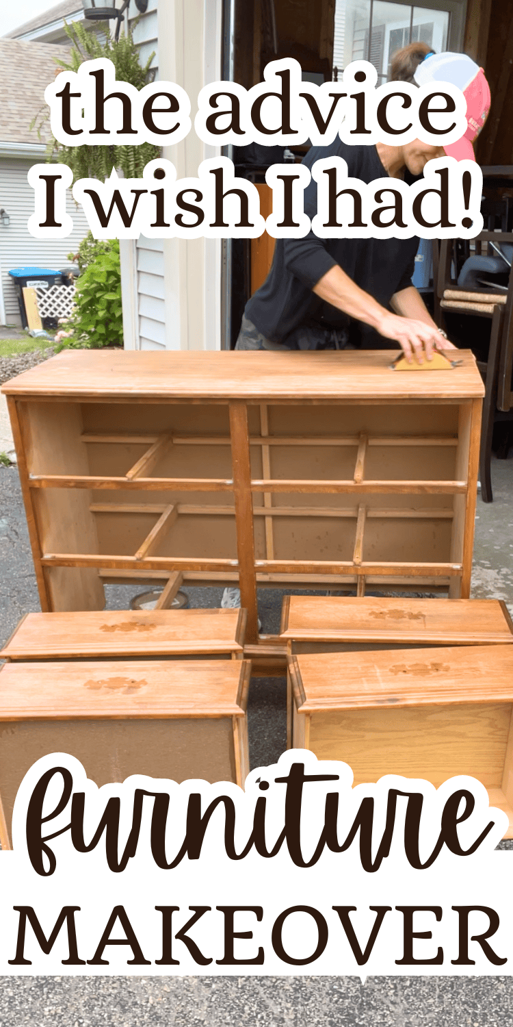 A person sanding a wooden dresser frame, with its drawers removed, in an outdoor setting near a garage.