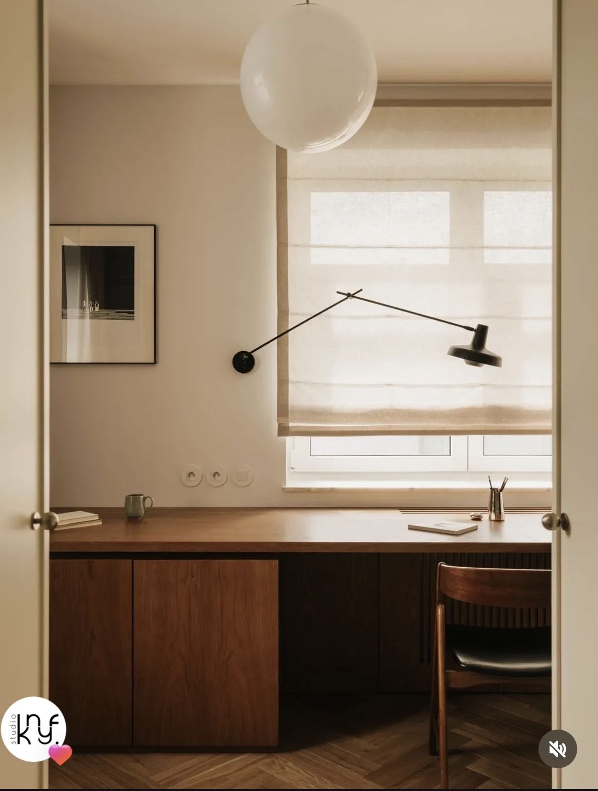 Home office with a wall-mounted task lamp positioned over a wooden desk near a window.