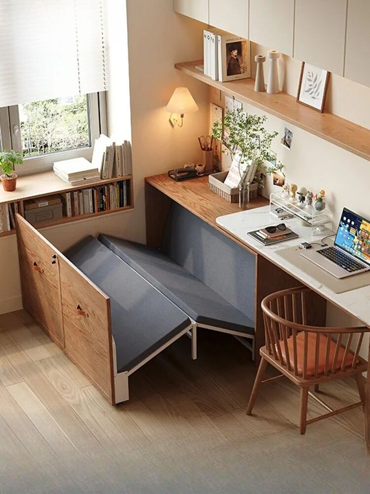 Small office nook with a desk and shelving, next to a fold-out bed partially extended from a cabinet.