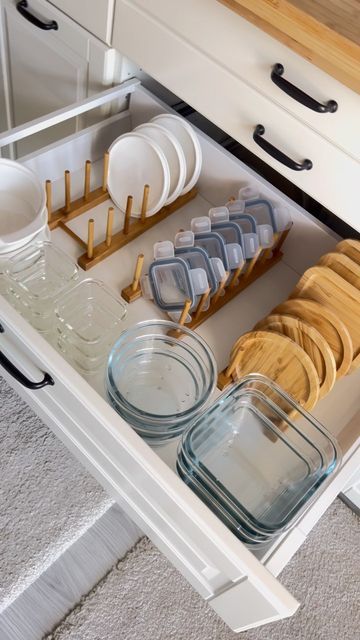 An organized kitchen drawer with glass food containers, bamboo lids, and white plastic lids stored upright using wooden peg…