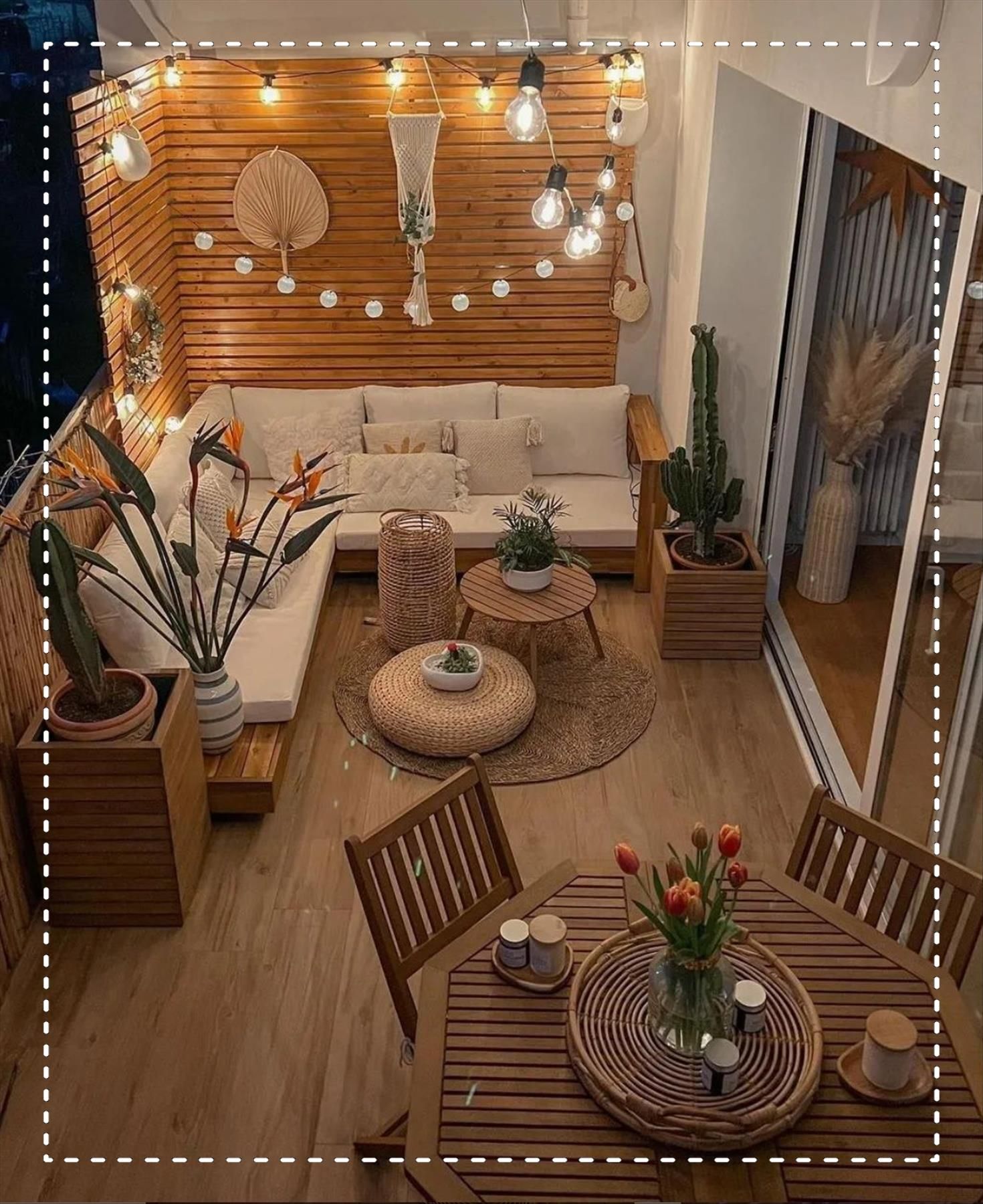 An outdoor patio with wooden slatted walls, string lights, and a combination of lounge seating and a small dining table.