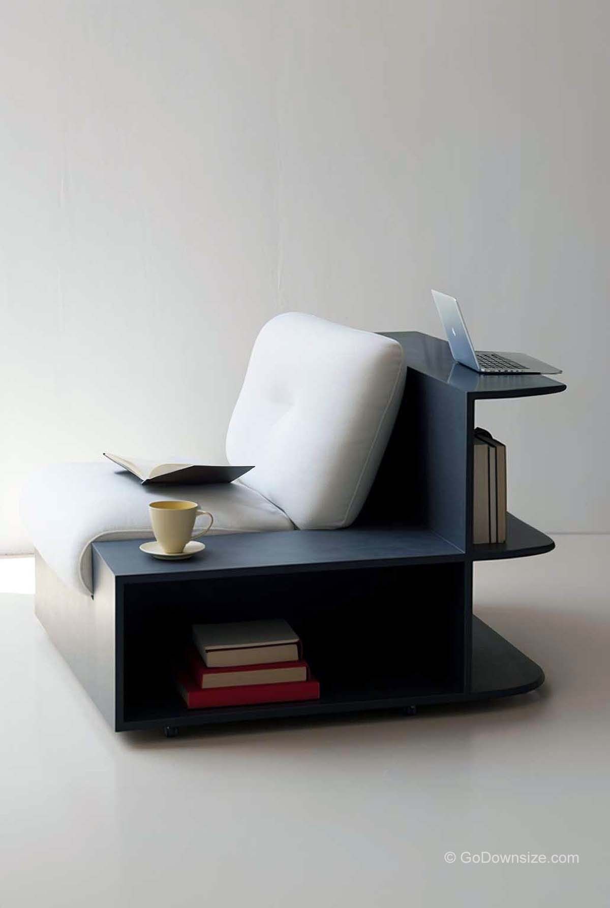 Single lounge chair with white cushion, dark blue integrated shelves, a laptop, and books.