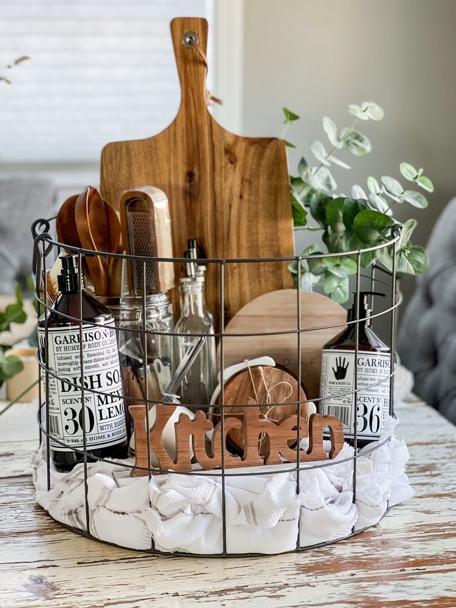 Wire basket filled with dish soap, a wooden cutting board, citrus juicer, grater, oil bottle, small wooden coasters, and a…