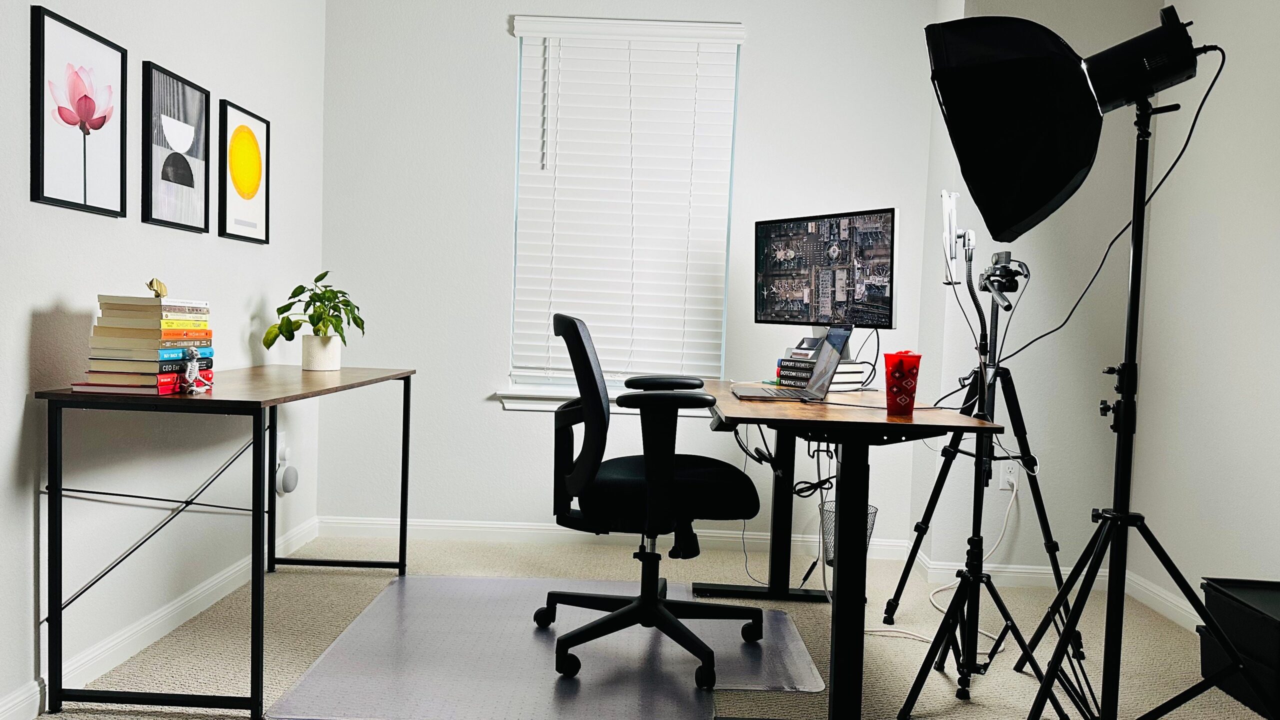 Desk workspace with a laptop, monitor, desk lamp, and warm room lighting