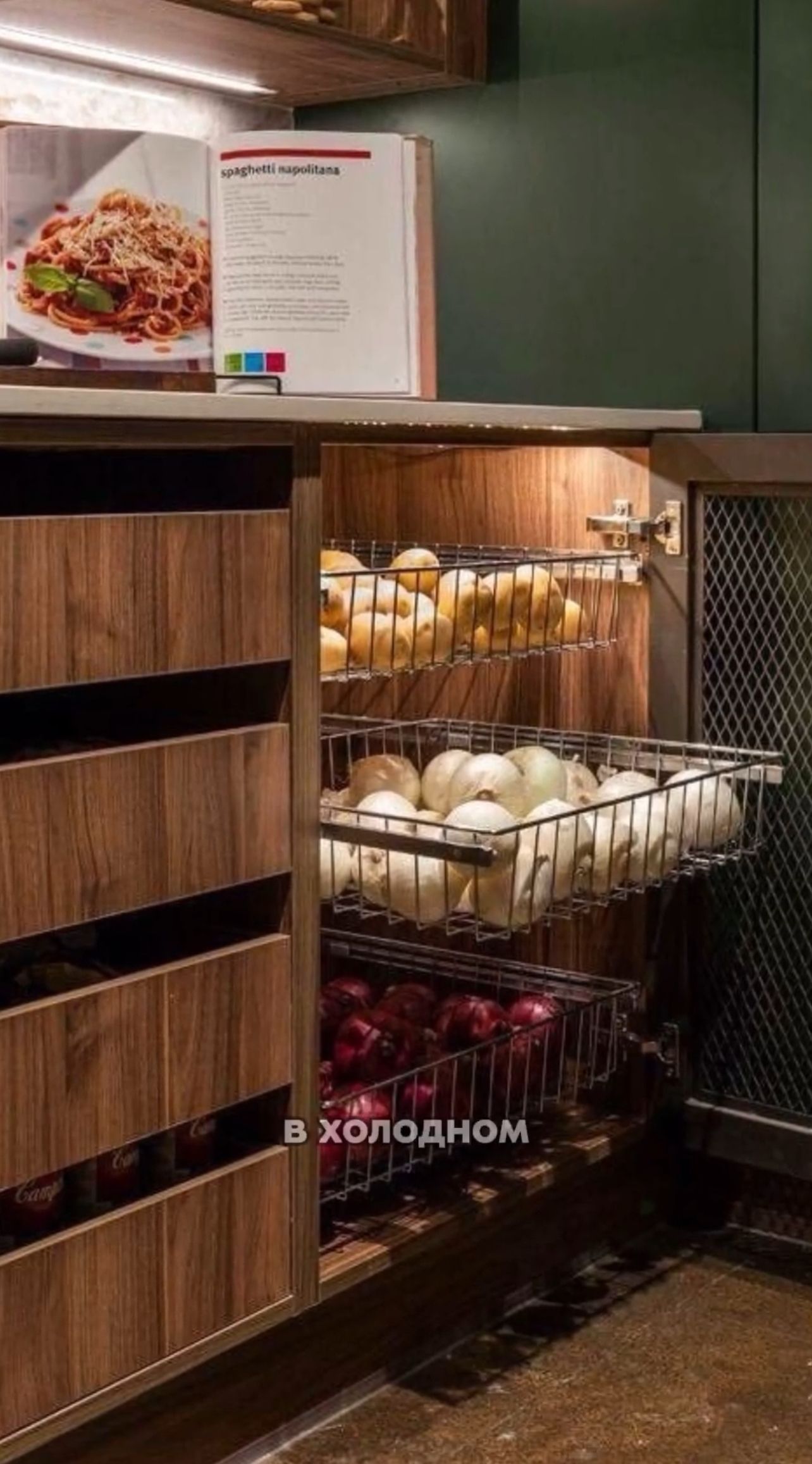 Built-in wooden kitchen cabinet with three wire pull-out bins filled with potatoes, white onions, and red onions.