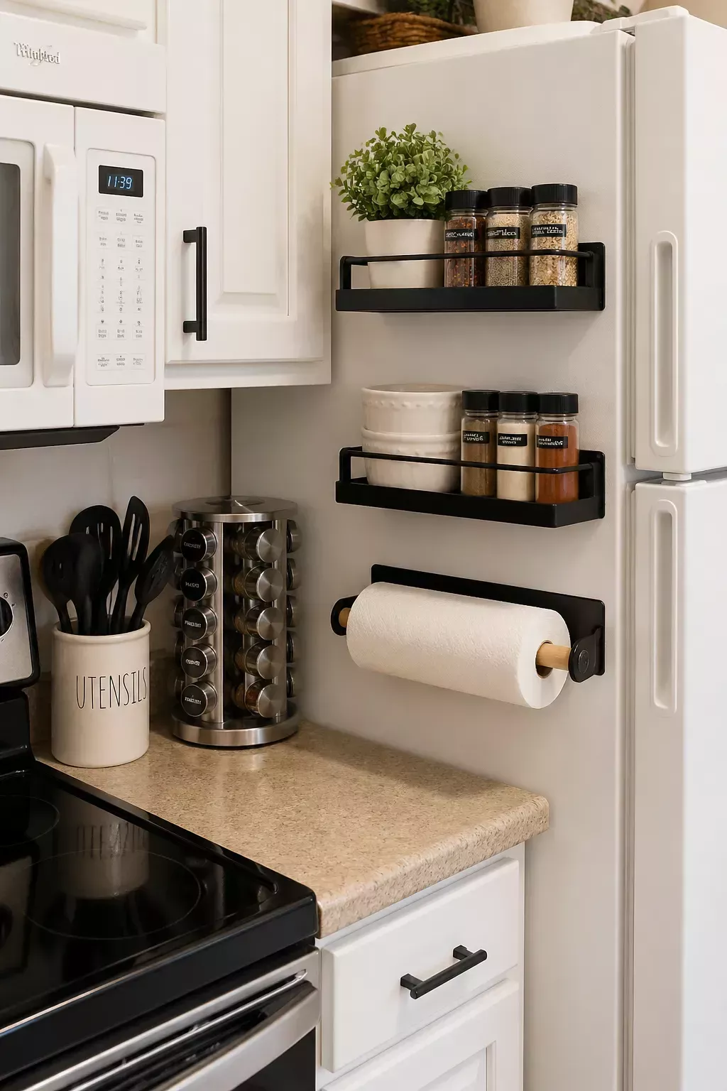 Magnetic shelves and a paper towel holder attached to the side of a white refrigerator, holding spices and a small plant.