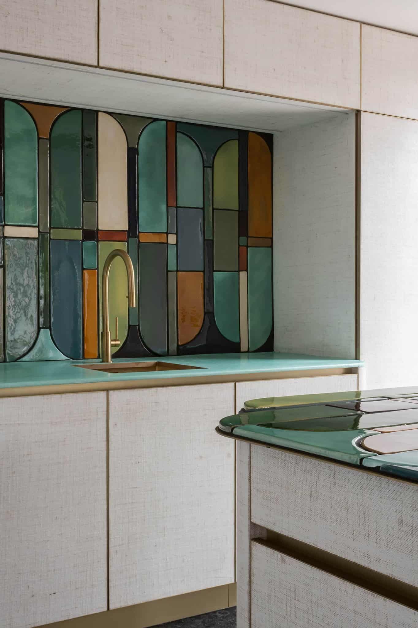 A kitchen backsplash featuring geometric tiles in green, blue, brown, with a matching countertop.