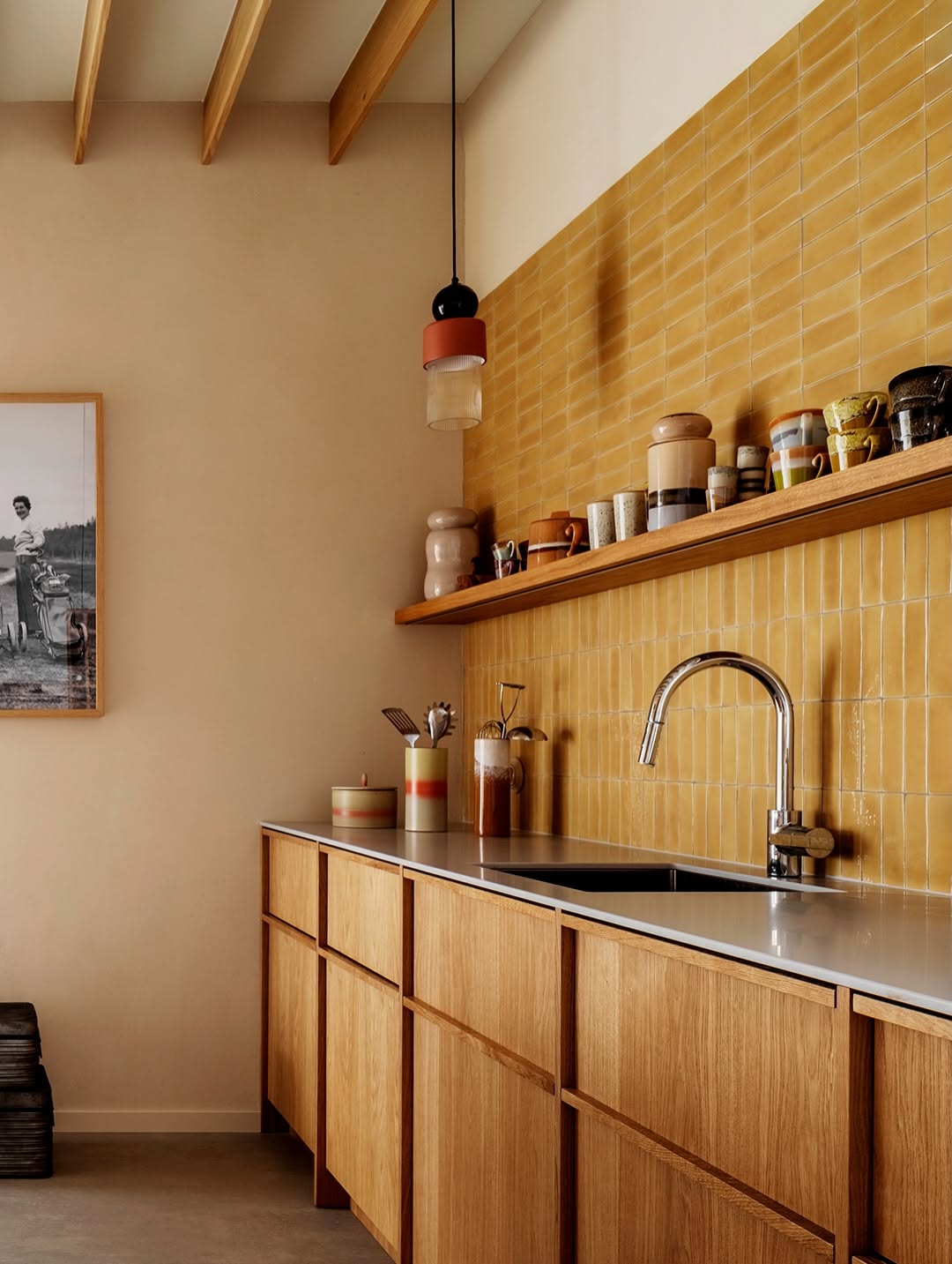 Kitchen with yellow subway tile backsplash, chrome faucet, and honey-toned wooden cabinets.