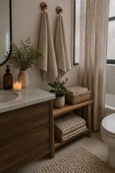 Neutral bathroom with two light woven towels hanging on wood hooks above a wooden vanity.