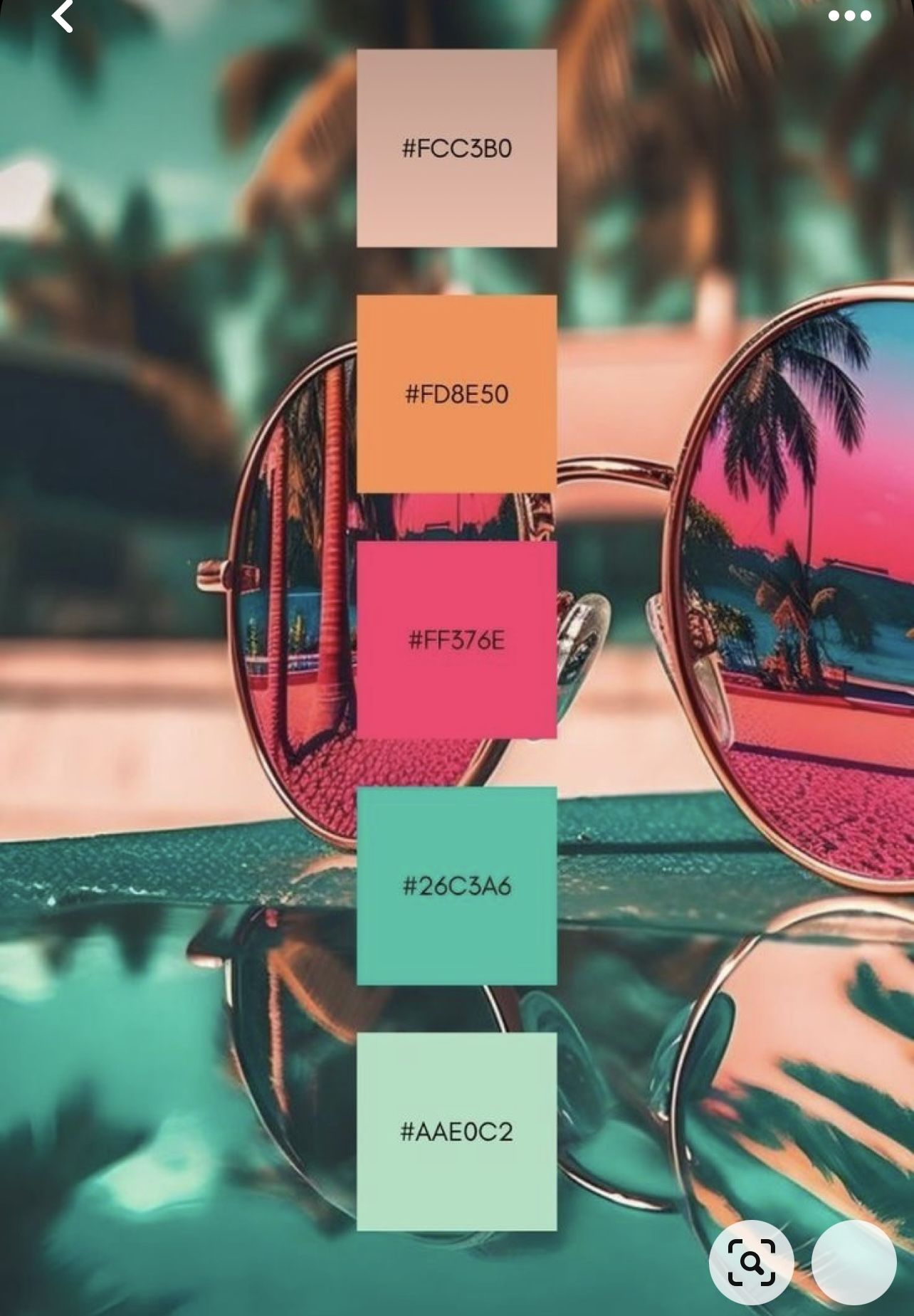Round, reflective sunglasses show an inverted reflection of palm trees and a vibrant pink and orange sunset.