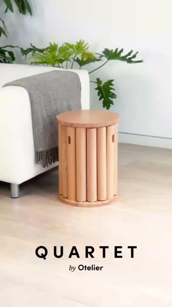 Cylindrical wooden stool or side table next to a white sofa with a gray throw blanket.