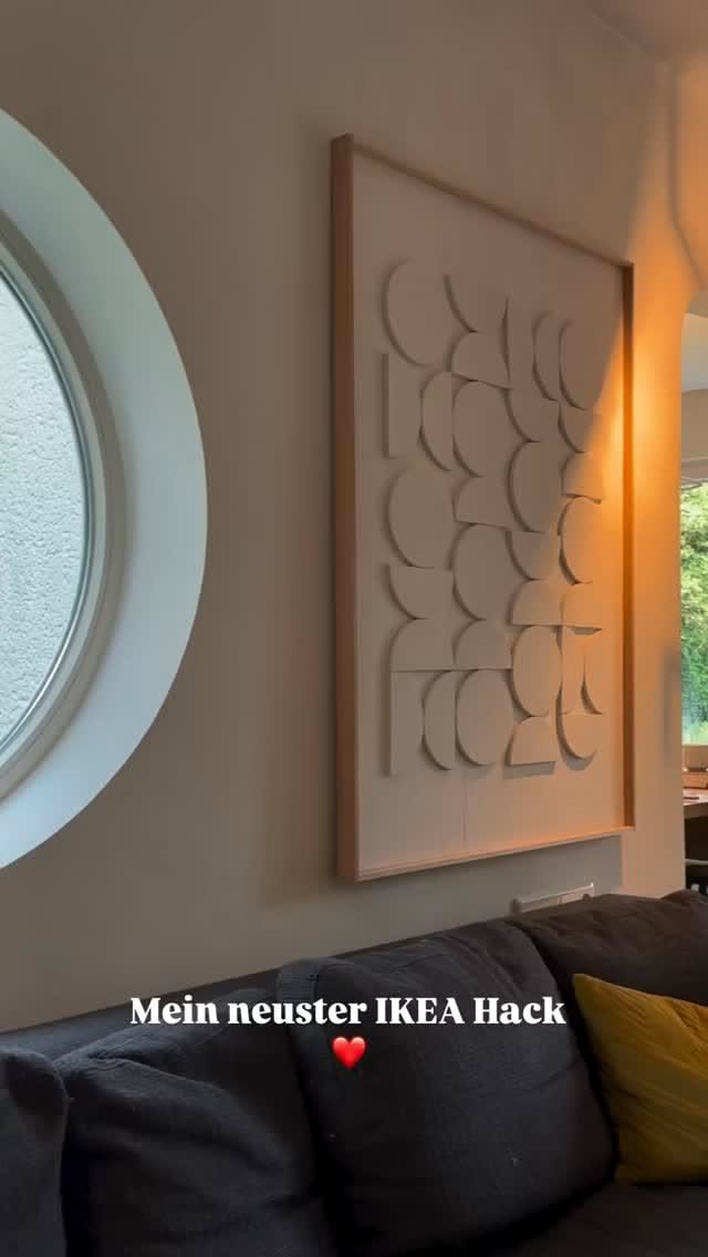 Large framed textured wall art with abstract shapes, hanging above a gray sofa with a yellow cushion