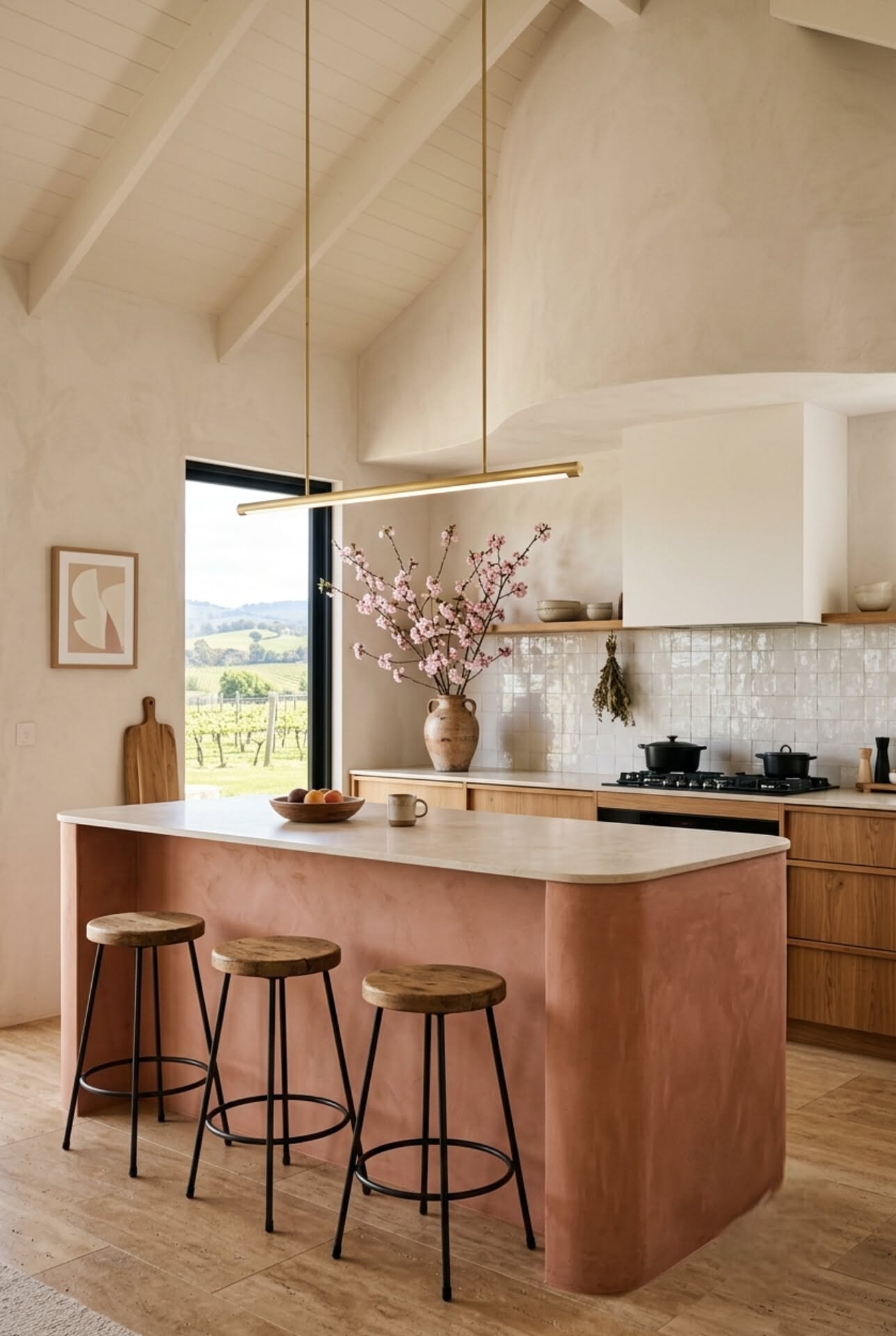 Kitchen island with curved terracotta base, light countertop, and three wooden stools, beside wood cabinets and a window.