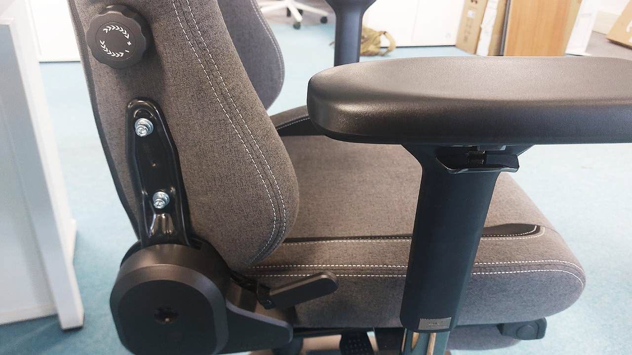 Close-up of a grey fabric ergonomic office chair with a wide seat and thick armrest