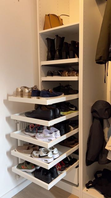 Closet interior with white pull-out shelves filled with various pairs of shoes, boots, and sneakers.