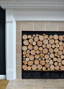 Close-up of a fireplace opening filled with neatly stacked, round wood logs of varying sizes.