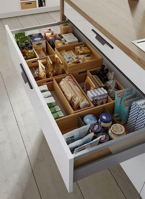 Kitchen drawer filled with various food items like spices, packages, and jars, neatly organized within modular wooden…