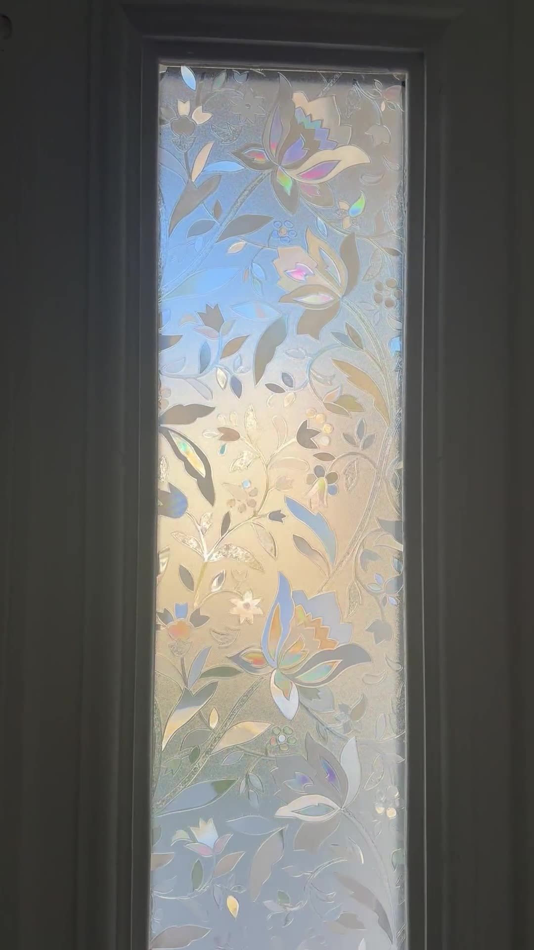 Close-up view of a door sidelight covered with a decorative floral privacy film.
