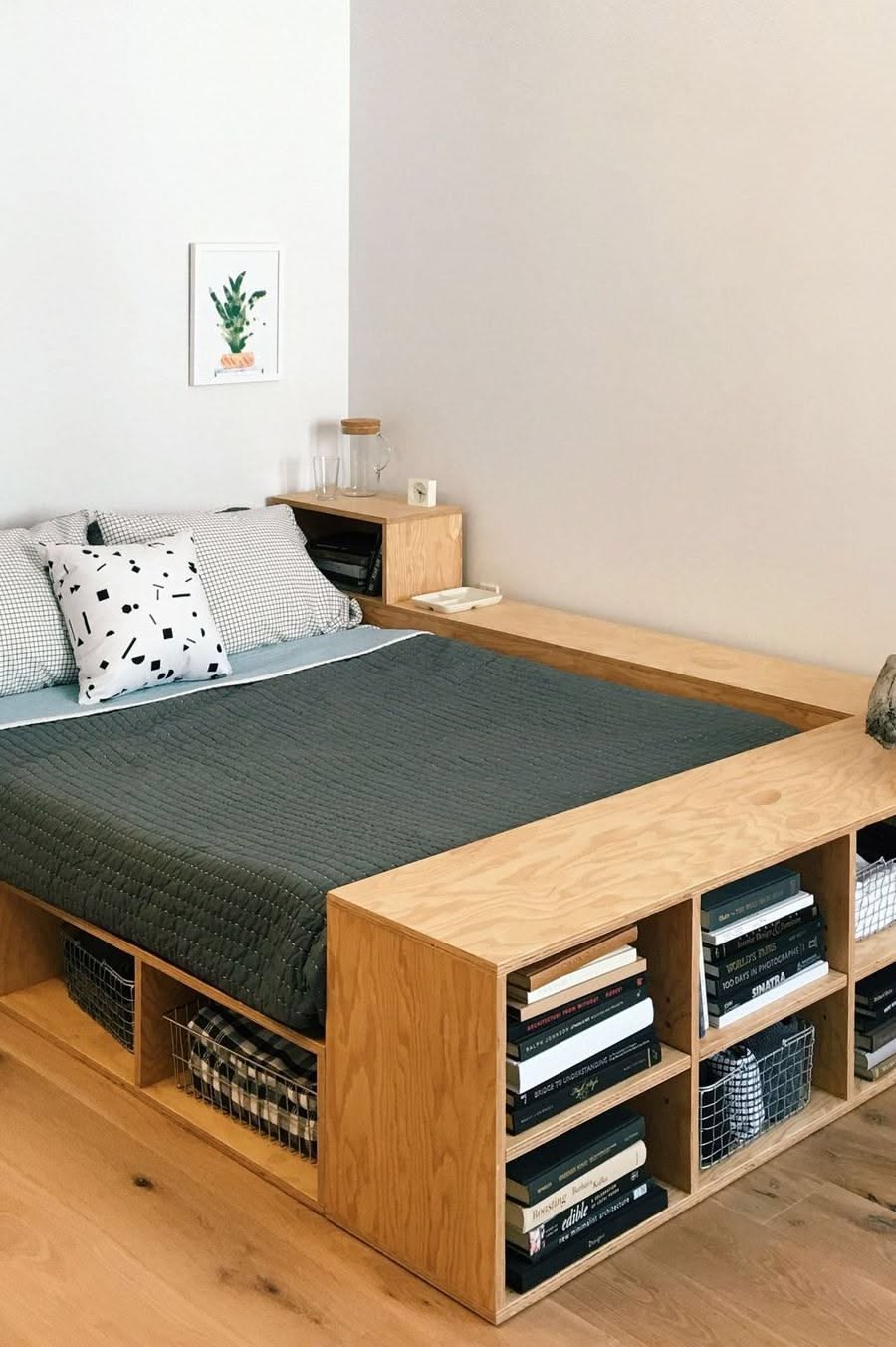 A wooden platform bed frame with built-in shelves and a headboard featuring a small side table.