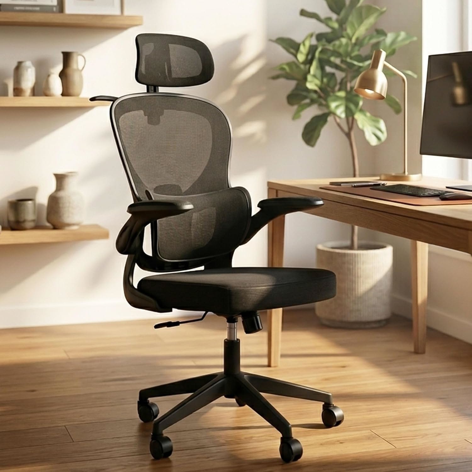 Black ergonomic office chair with a mesh back and headrest, next to a light wooden desk in a home office.