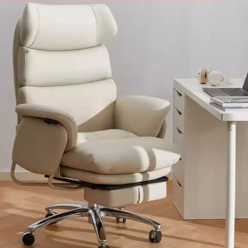 Cream-colored padded office chair with headrest and integrated footrest next to a white desk with a laptop