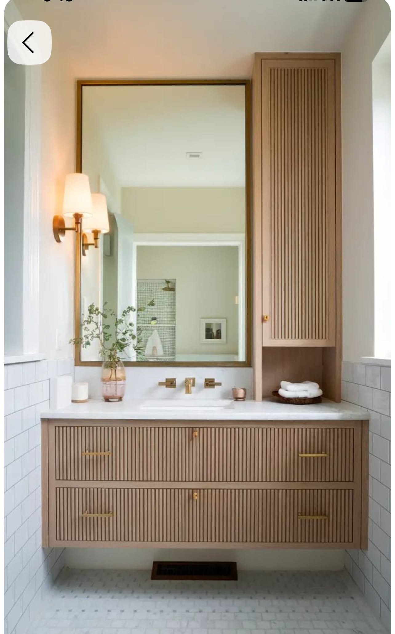 Bathroom vanity with light wood fluted drawers and a matching tall cabinet next to a mirror and sink.