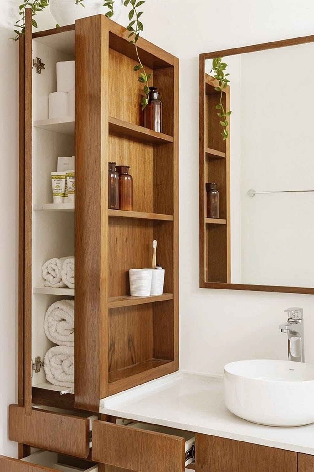 Wood-framed wall storage unit with open shelves, a hidden cabinet, and a matching mirror above a sink.