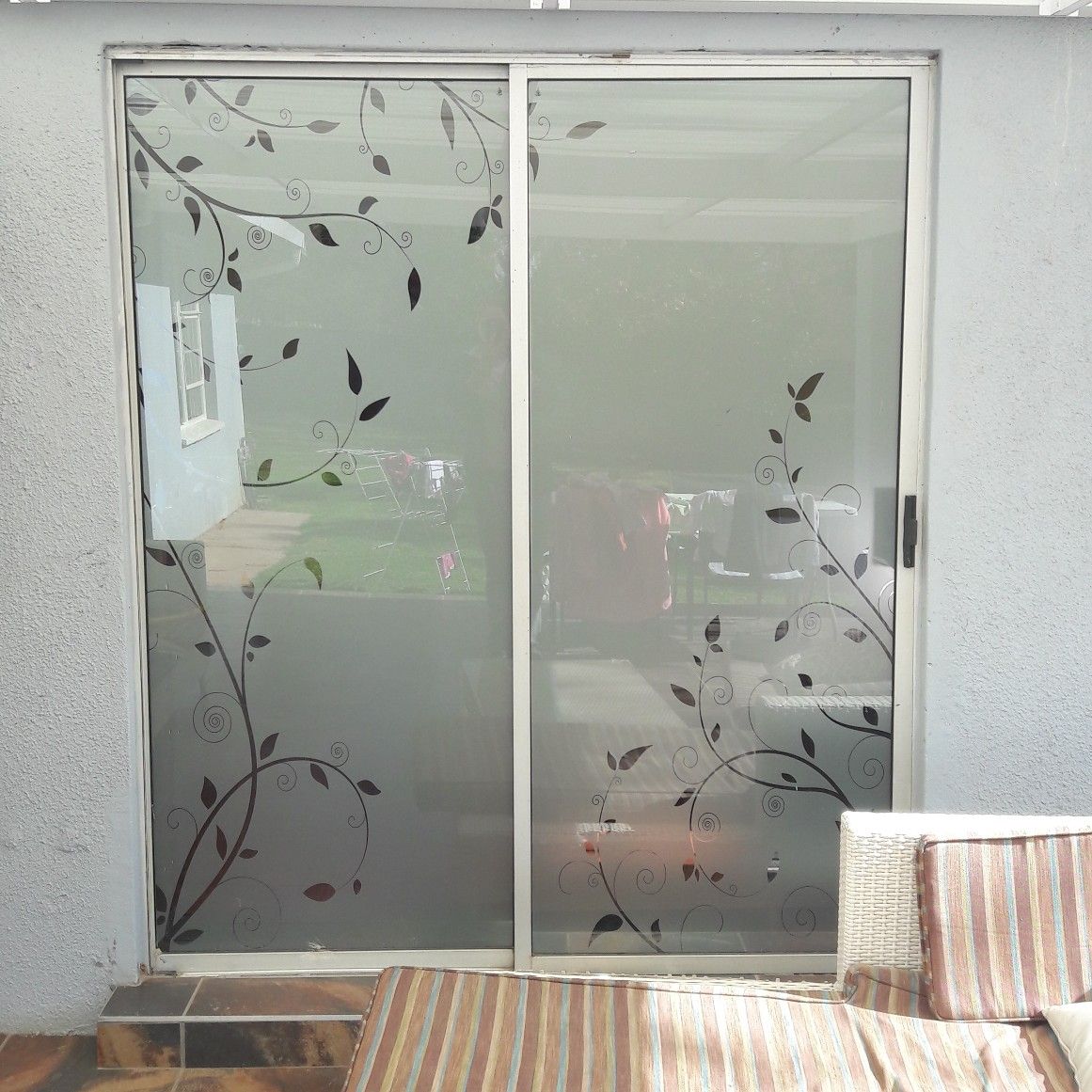 Sliding glass doors with a frosted film featuring an etched-look vine and leaf pattern along the bottom and sides.