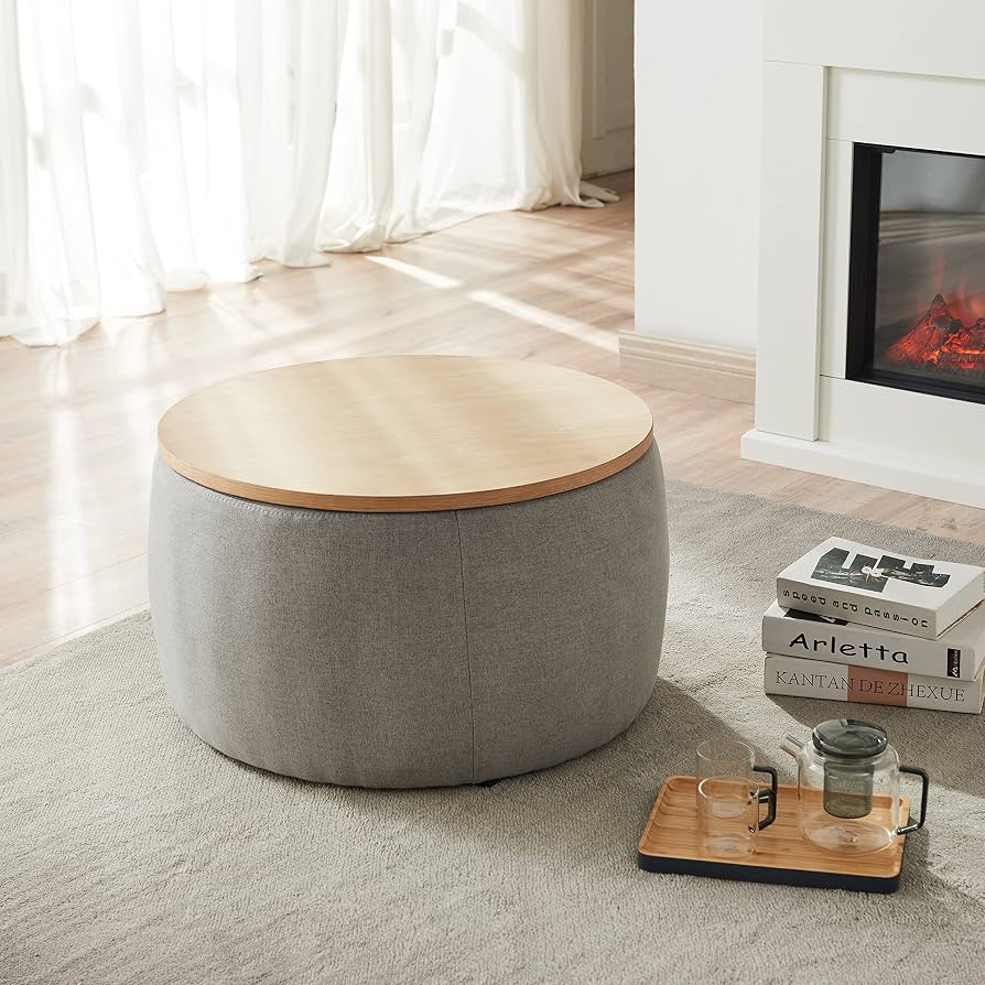 Dark gray round upholstered storage ottoman with a removable top beside a sofa.
