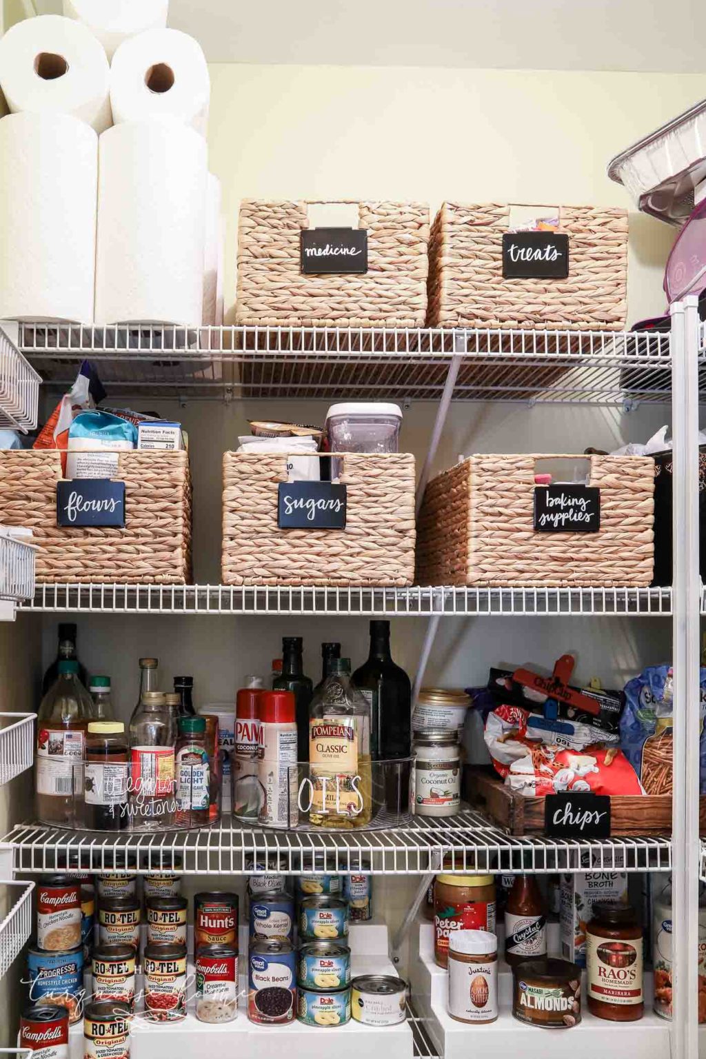 Organized pantry shelves with baskets, jars, canned goods, and food containers