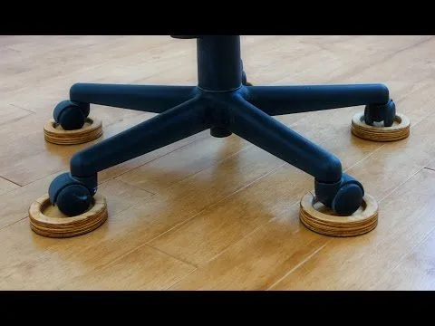 An office chair with five wheels, each resting in a round, wooden coaster on a hardwood floor.