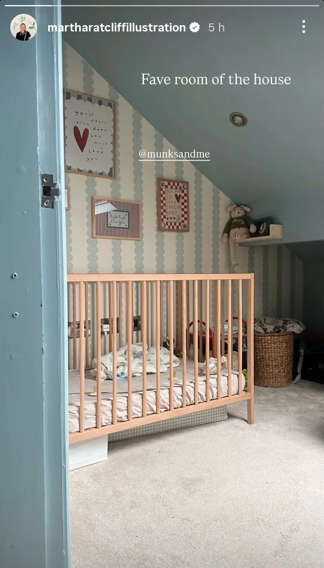 Wooden crib positioned against a sloped wall with light blue and white patterned wallpaper, under a blue ceiling.